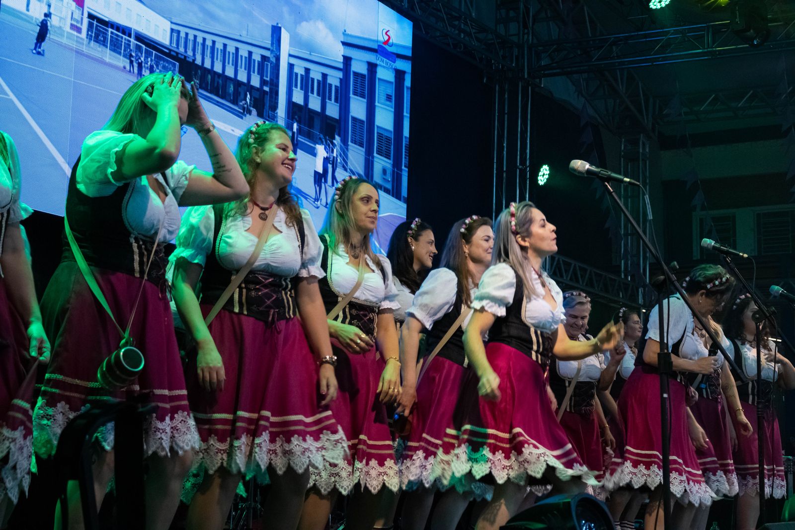 Grupo de dança folclórica em trajes típicos se apresentando no palco da festa