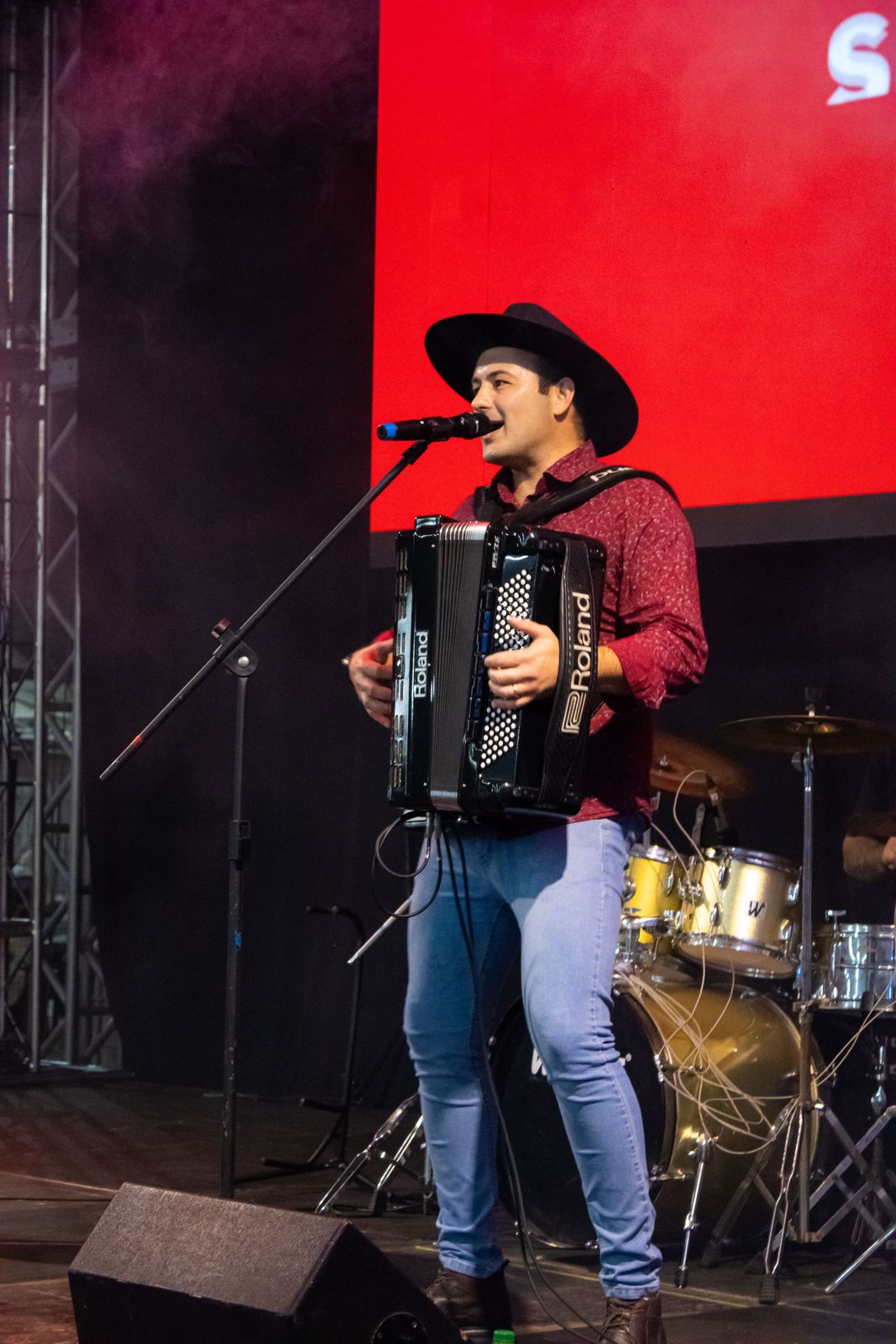 Músico cantando e tocando violão durante as atrações da festa